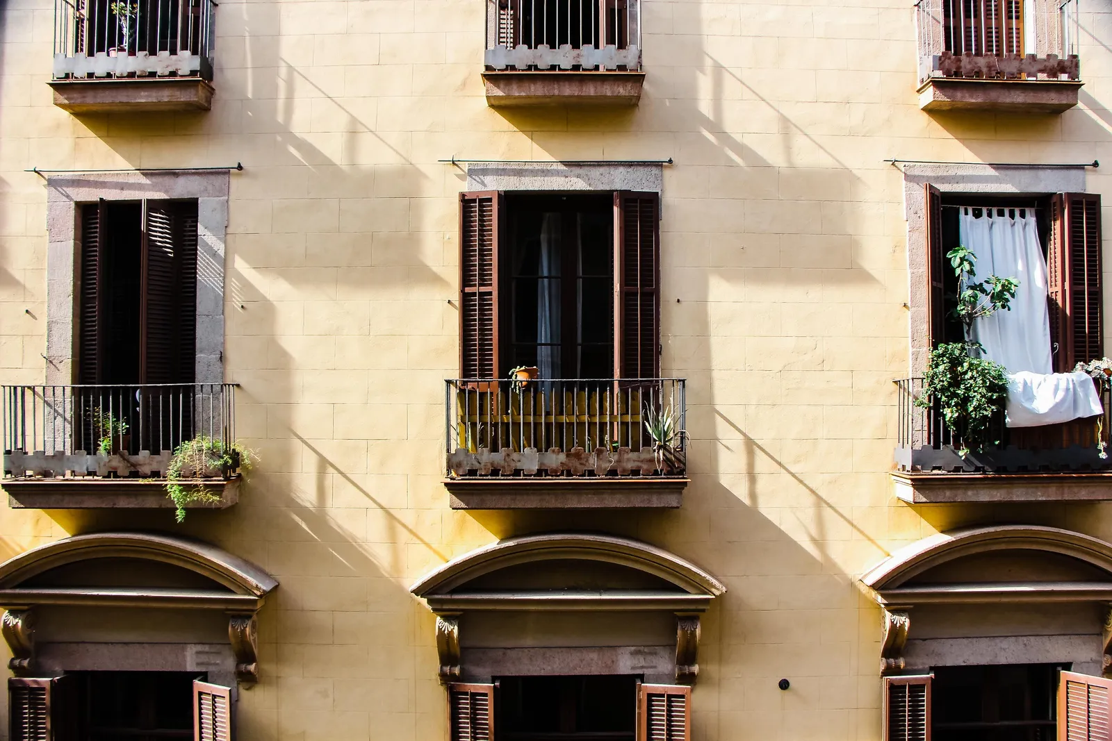 Fachada de un edificio clásico con balcones de hierro y persianas de madera